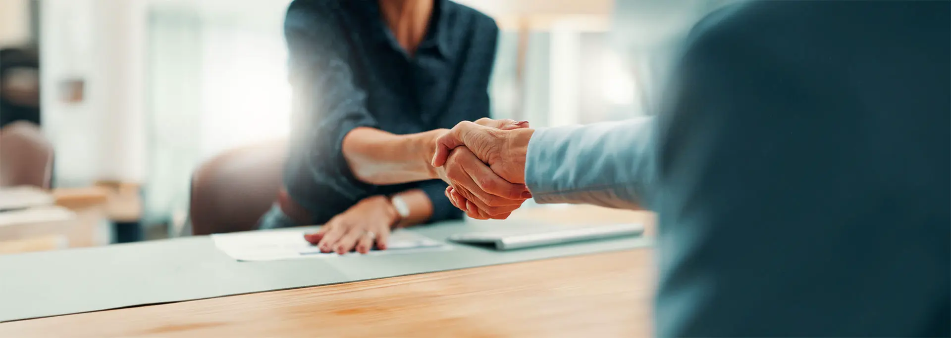 A woman and a man sitting at a table shaking hands